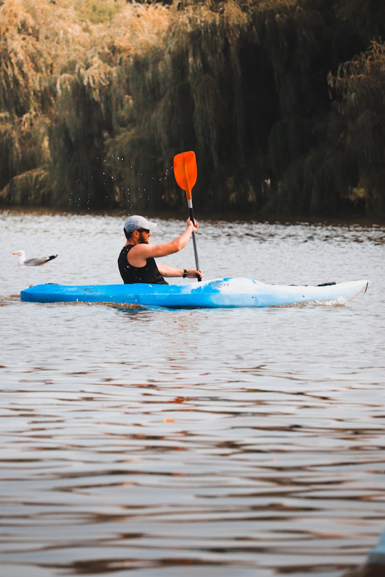 A Man In Black Tank Top Sitting On A Kayak While Paddling