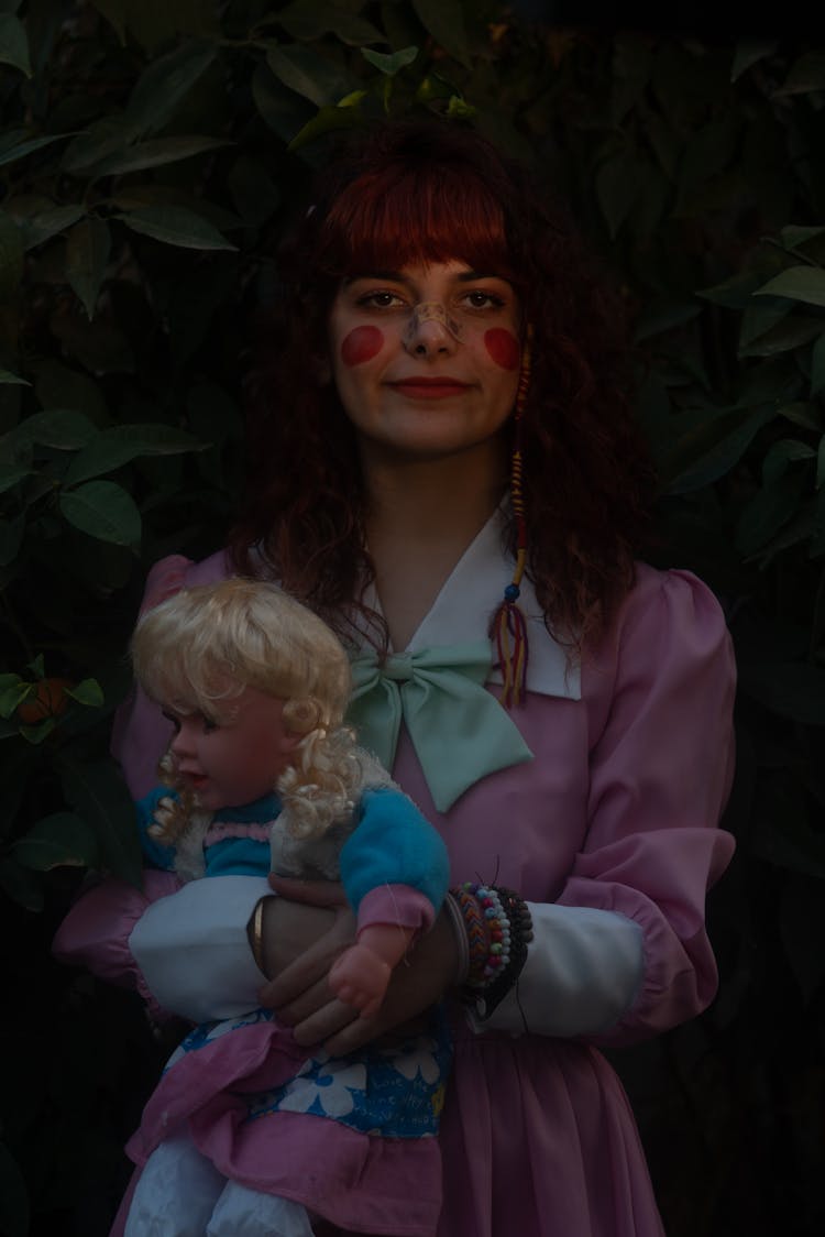 A Woman In Pink Dress Holding A Doll