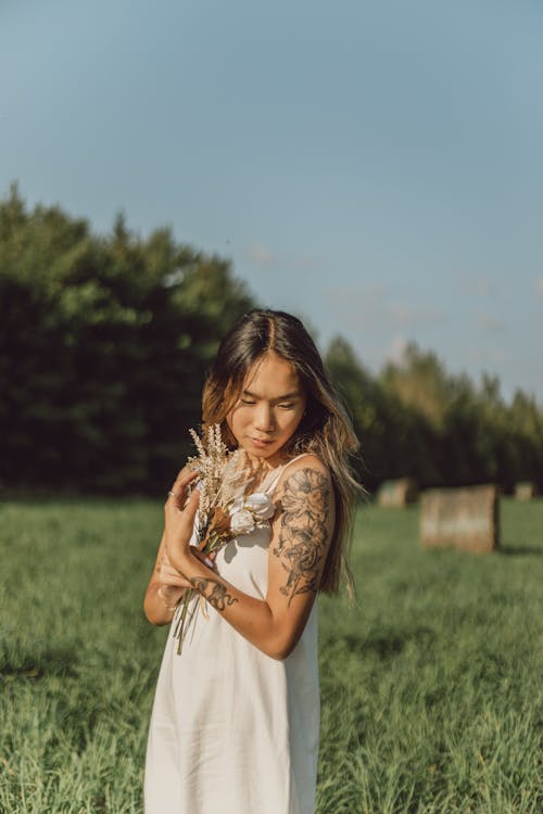 Free A Woman Holding Flowers in the Farm Field Stock Photo