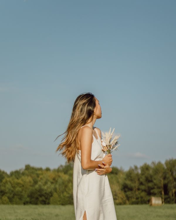 A Woman in White Dress Holding Flowers · Free Stock Photo