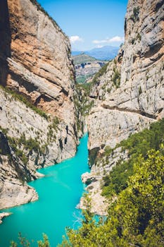 Breathtaking aerial shot of Congost de Mont-rebei Gorge in Lleida, Spain, showcasing clear blue waters and rugged cliffs.