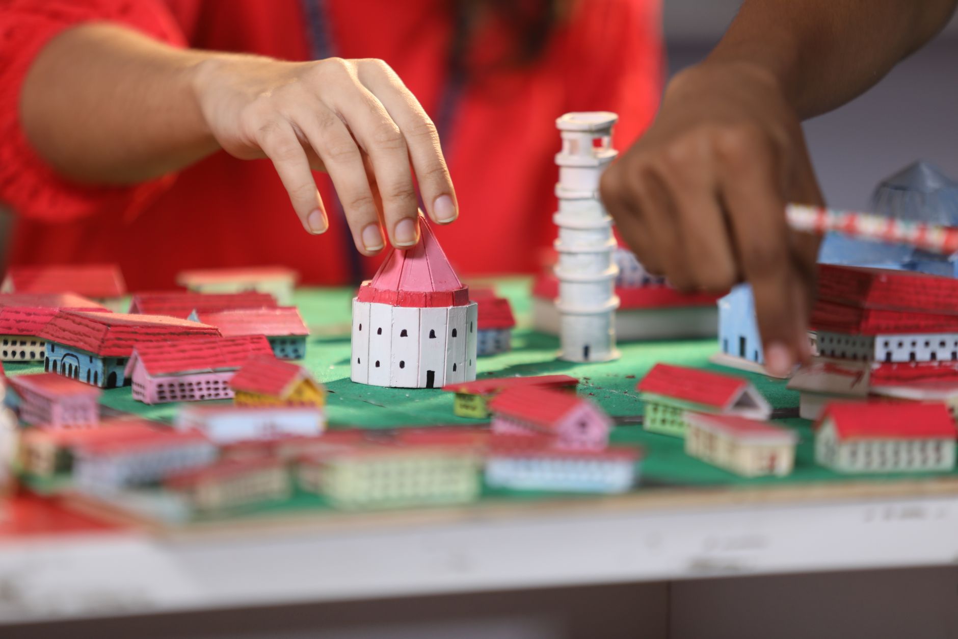 Hands engaging with a colorful miniature town model, focusing on creativity and craftsmanship.