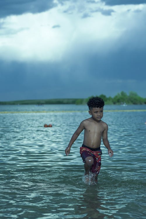 Topless Boy in Red Shorts Standing on Water
