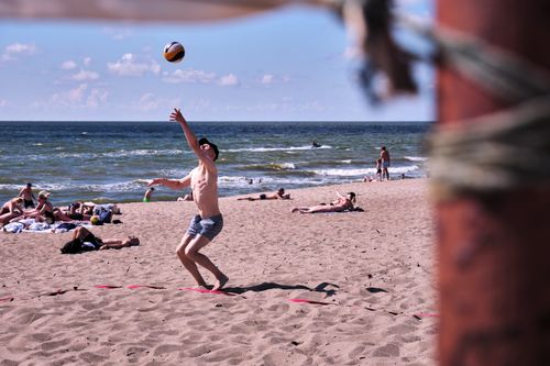 Free A young man enjoying a game of beach volleyball on a sunny day with the ocean in the background. Stock Photo