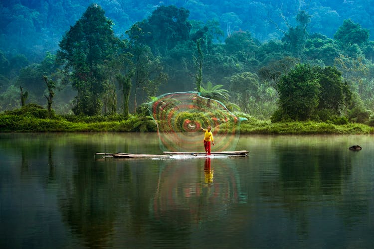 A Fisherman Throwing A Fish Net On The Lake