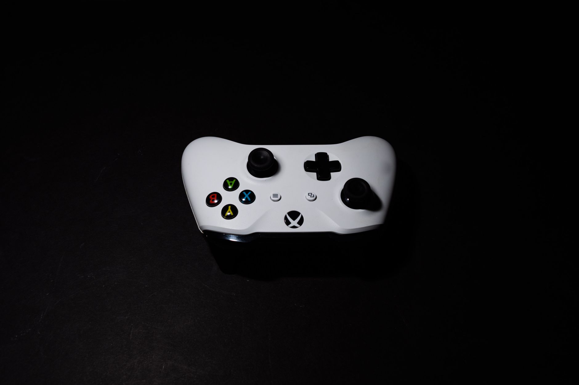 A close-up of a white Xbox controller on a black background, highlighting its modern design.