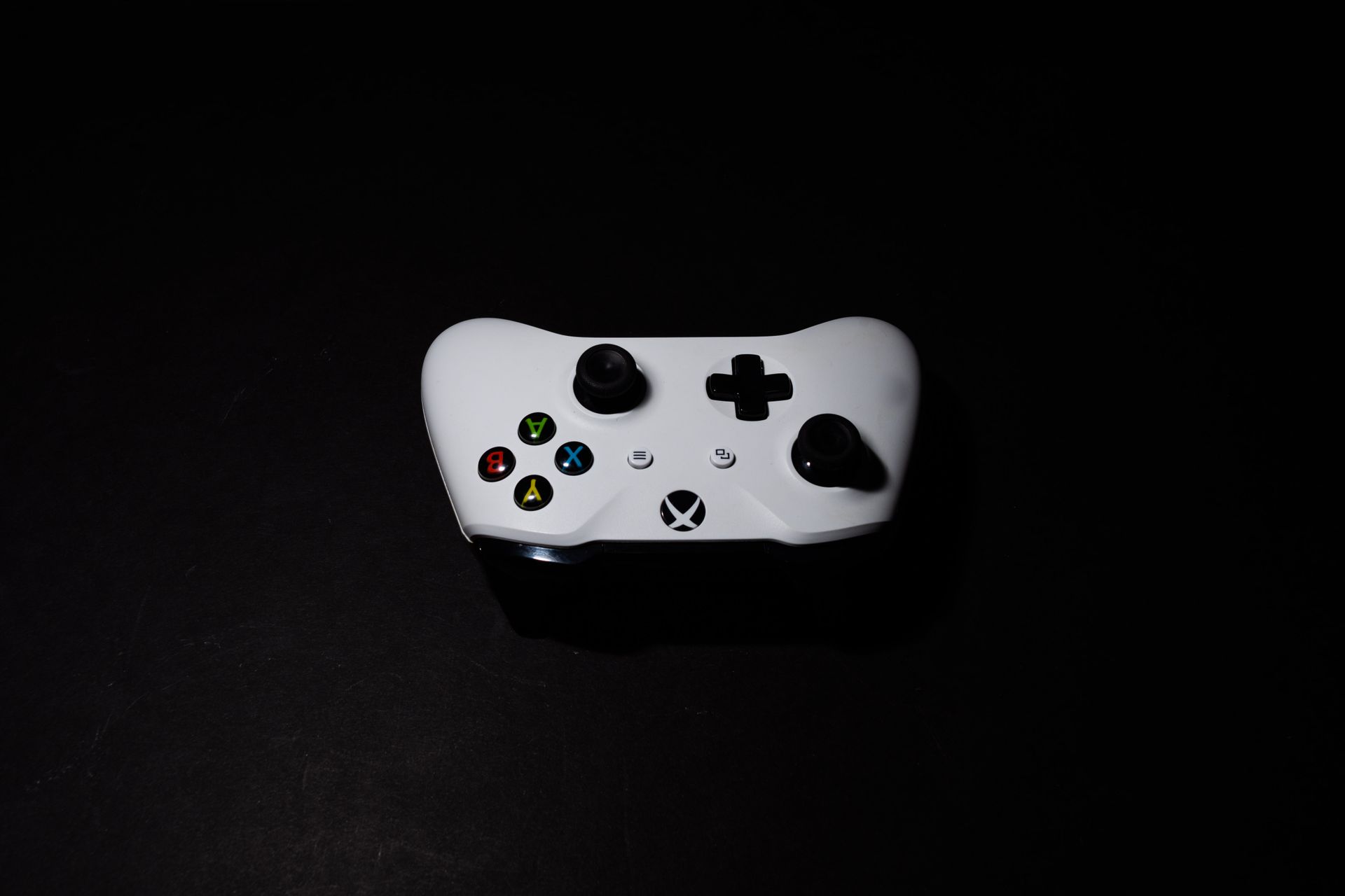 A close-up of a white Xbox controller on a black background, highlighting its modern design.