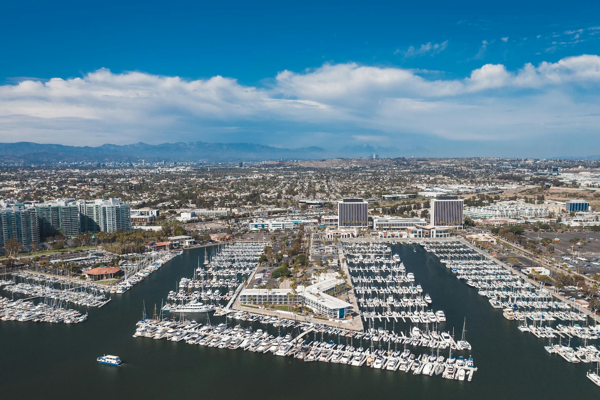 Stunning aerial view of a bustling marina harbor in Los Angeles with boats and cityscape.