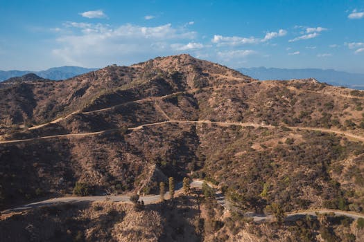 Scenic aerial view of dry, rugged mountain landscape with winding roads on a clear day.