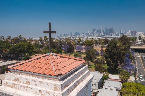 Free A stunning aerial view of a church roof overlooking the vibrant Los Angeles skyline under a clear blue sky. Stock Photo