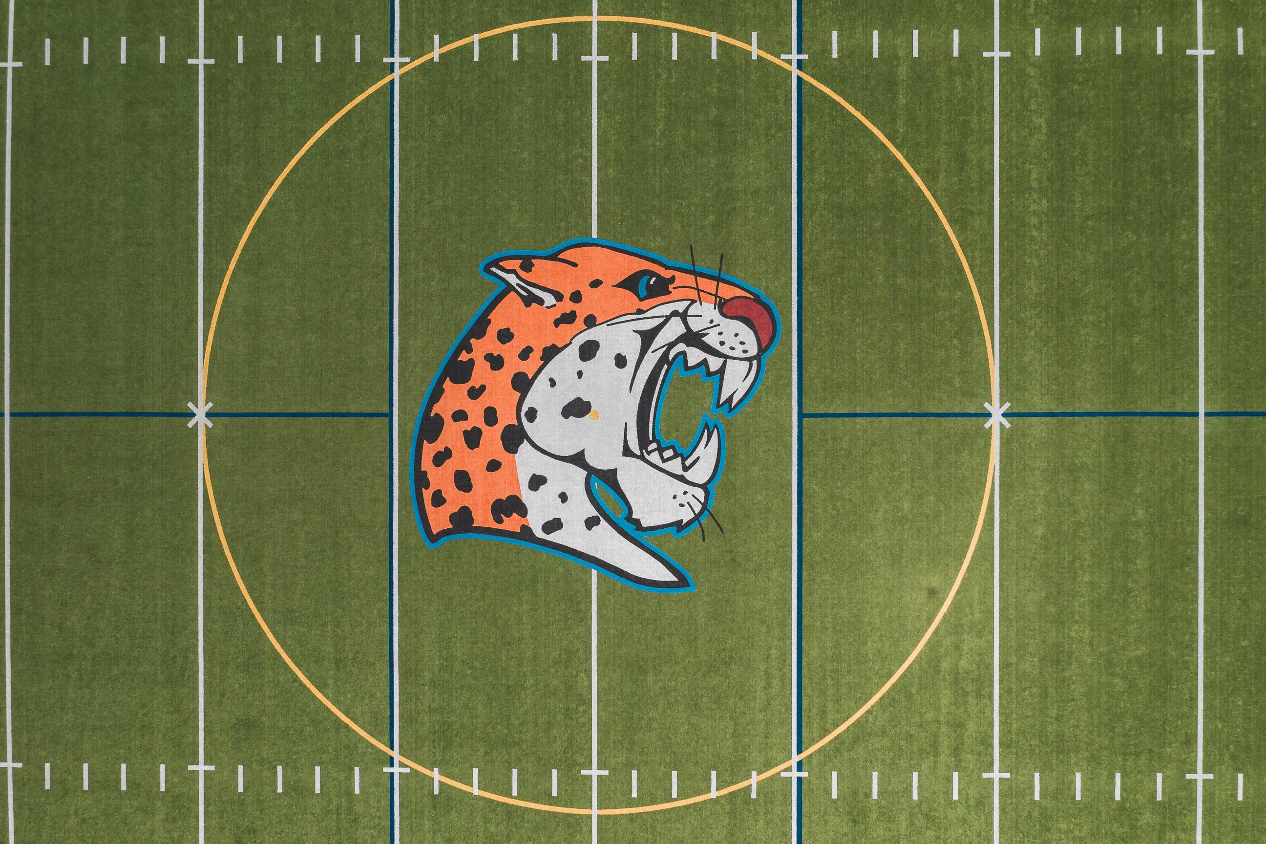 Drone shot of a football field featuring a prominent jaguar logo in the center circle.
