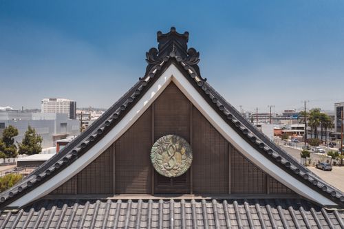 Free A traditional Japanese temple roof with urban cityscape in the background on a sunny day. Stock Photo