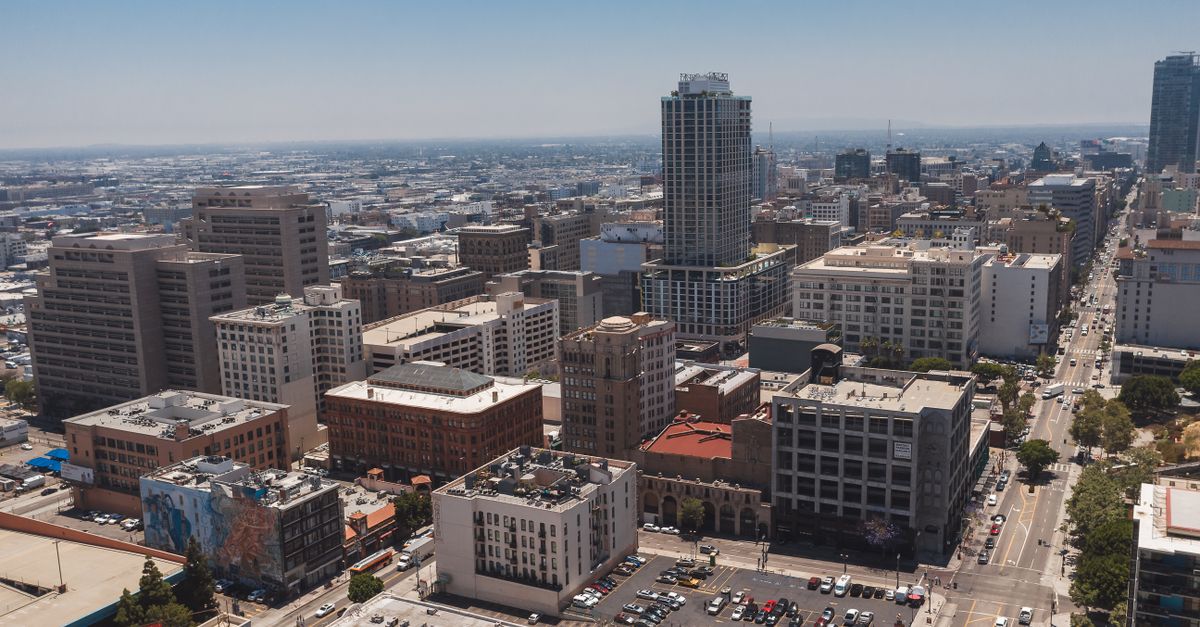 Panoramic aerial shot capturing downtown Los Angeles with skyscrapers and urban streets.