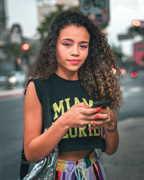 Free A Woman with Curly Hair Using Her Smartphone Stock Photo