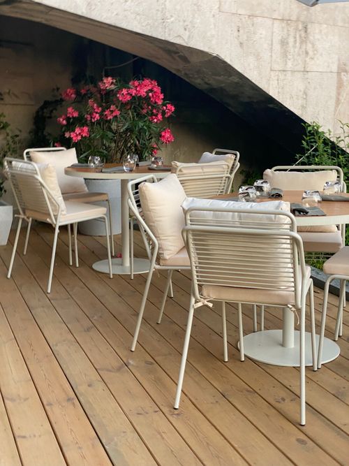 Free Elegant outdoor cafe setup with modern chairs and floral decor for a serene dining experience. Stock Photo