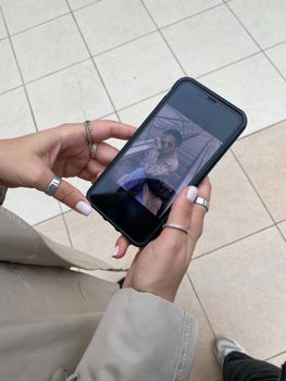 Close-up of hands holding a smartphone showing a fashion photo outdoors.