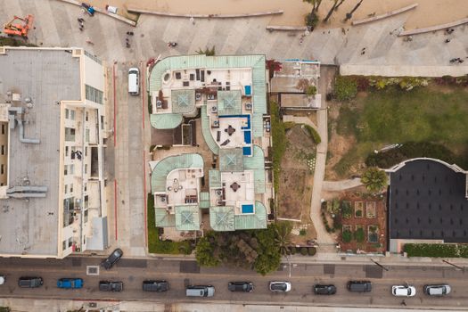 Drone shot capturing urban buildings, road traffic, and adjacent park area from above.