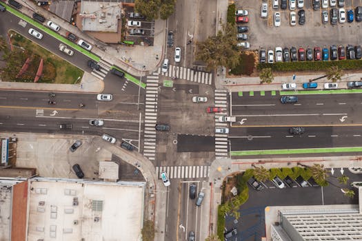 Drone shot of a busy city intersection with cars and parking lots around.