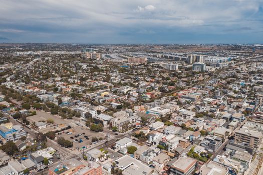 Aerial drone view of expansive urban cityscape with residential and commercial buildings under a blue sky.