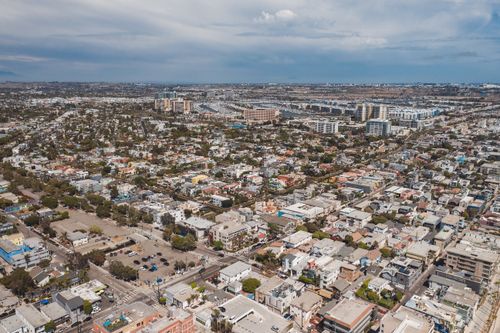 Free Aerial drone view of expansive urban cityscape with residential and commercial buildings under a blue sky. Stock Photo