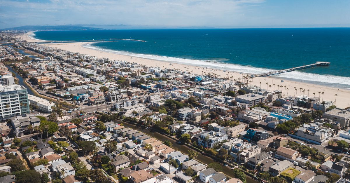 A stunning aerial view of a coastal urban city with a vibrant beach and pier.