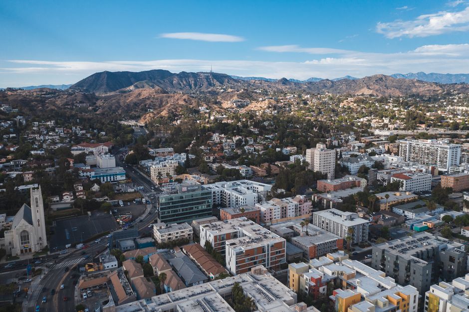 Aerial view of Los Angeles cityscape with mountains in the background on a clear day.