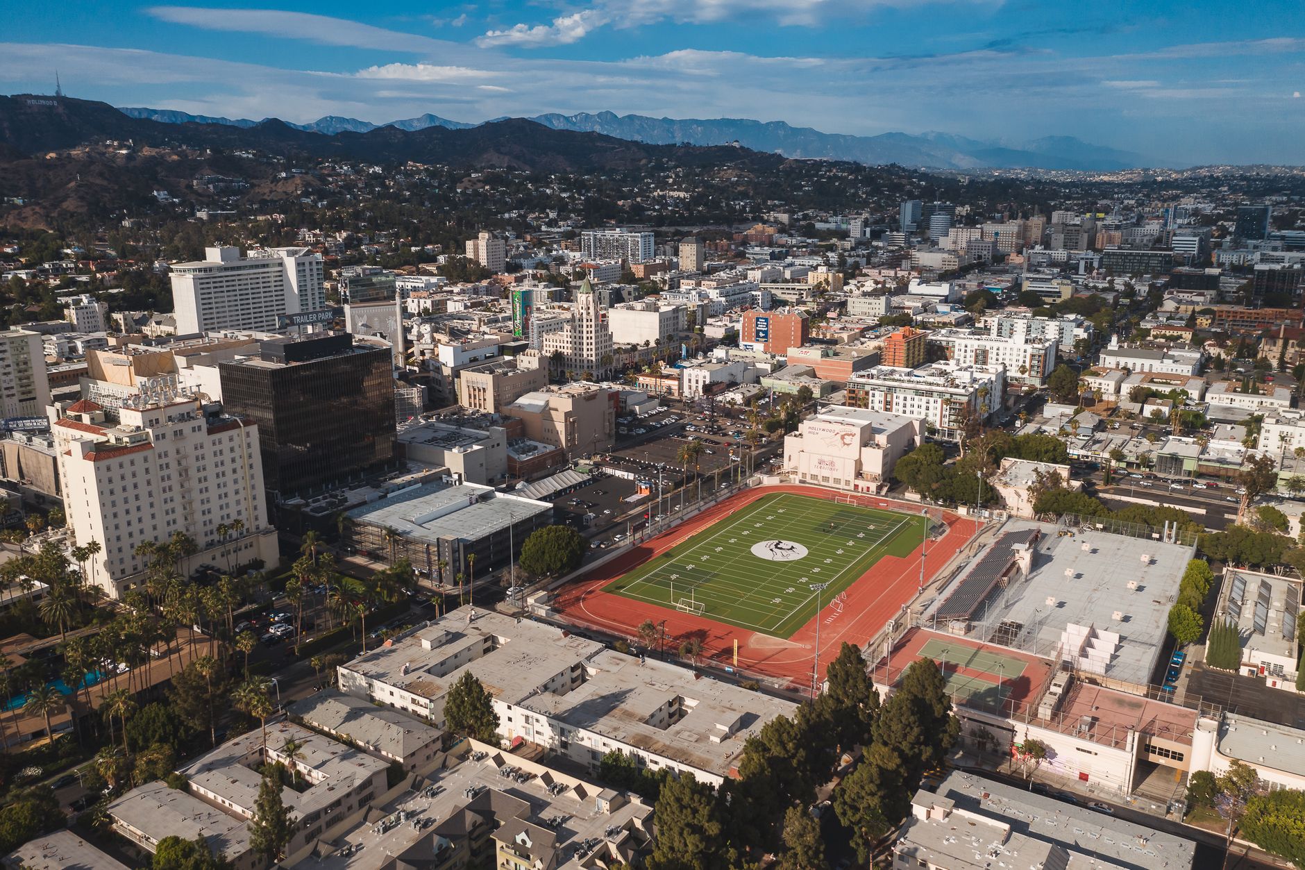 Stunning aerial view of Los Angeles cityscape featuring a prominent football field in the foreground.