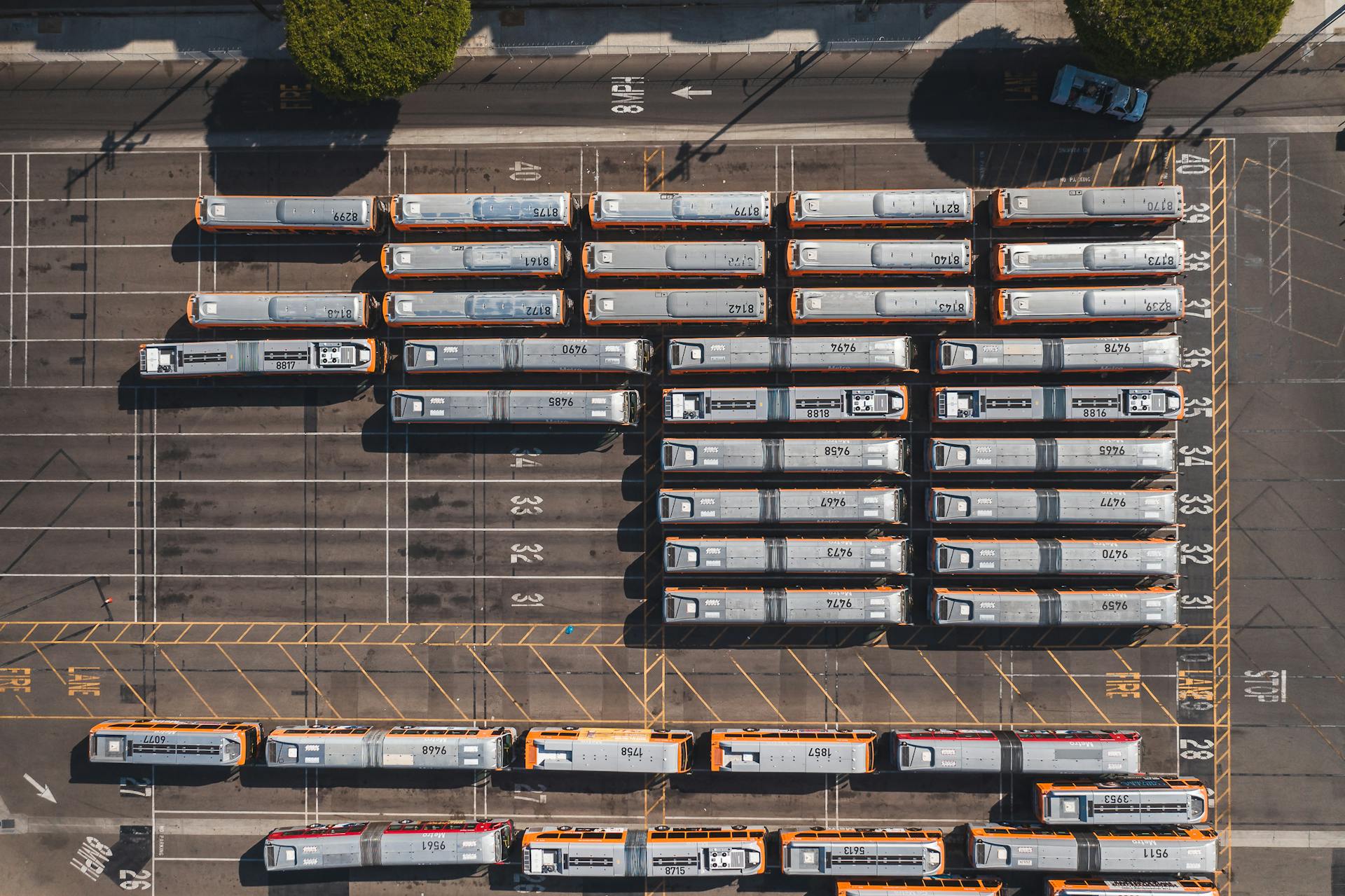 Aerial shot of a bus parking lot with vehicles neatly lined up in rows.