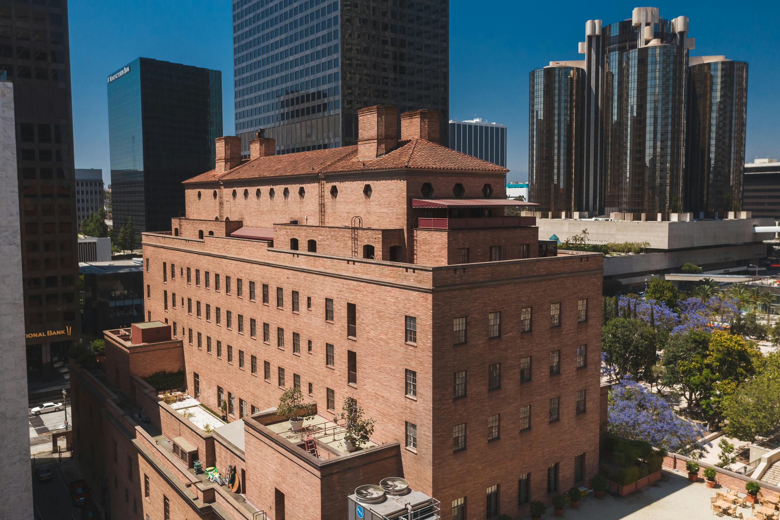Aerial view showcasing a historic brick building amidst modern skyscrapers in a vibrant cityscape.