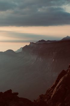 A breathtaking view of a mountain range during sunrise with dramatic clouds.
