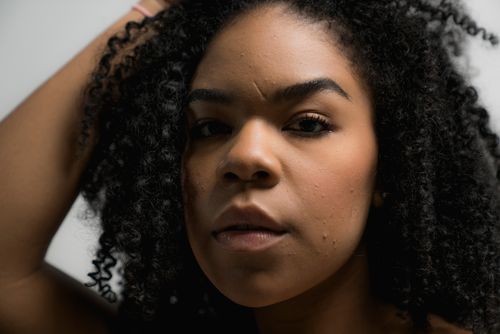 Free Close-up portrait of a beautiful woman with natural curly hair, showcasing confidence and grace. Stock Photo