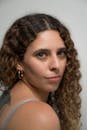 一位留着卷发、戴着圆环耳环的女人的特写肖像，回头看