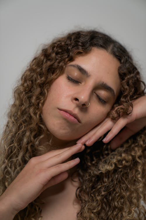 Woman Posing with her Eyes Closed and Hands under her Chin 