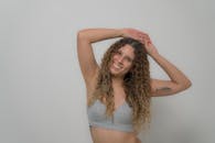 一位微笑的卷发女人的肖像，在工作室环境中穿着露脐上衣