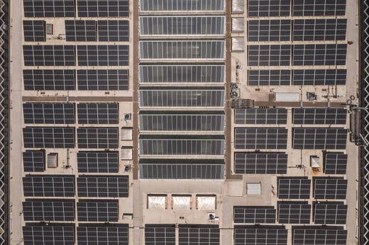 High angle drone shot of solar panels on a large rooftop