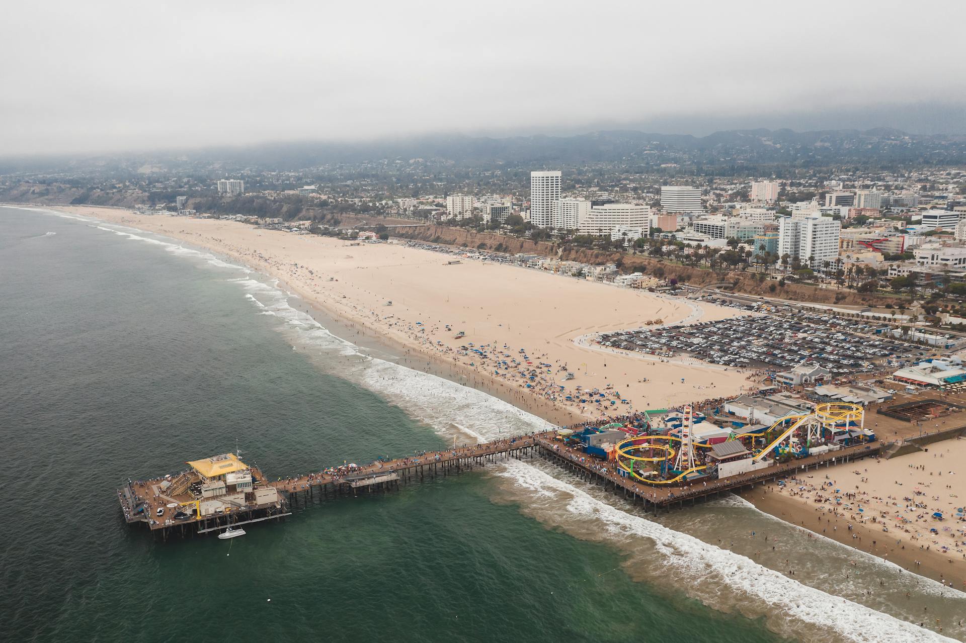 Aerial view of Santa Monica Pier with amusement park and beach in California.