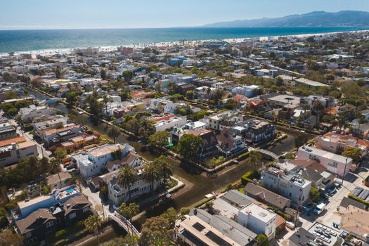 A vibrant aerial shot of a coastal residential neighborhood by the sea with visible canals and architecture.