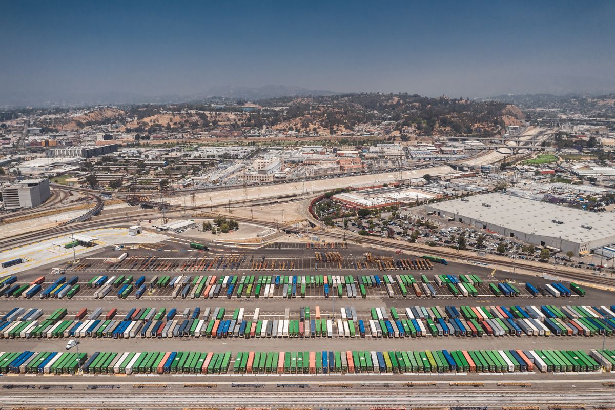 Aerial view showcasing colorful shipping containers and sprawling urban landscape.