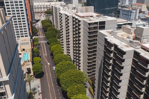 Drone shot showcasing a cityscape with tall apartment buildings and a tree-lined street.