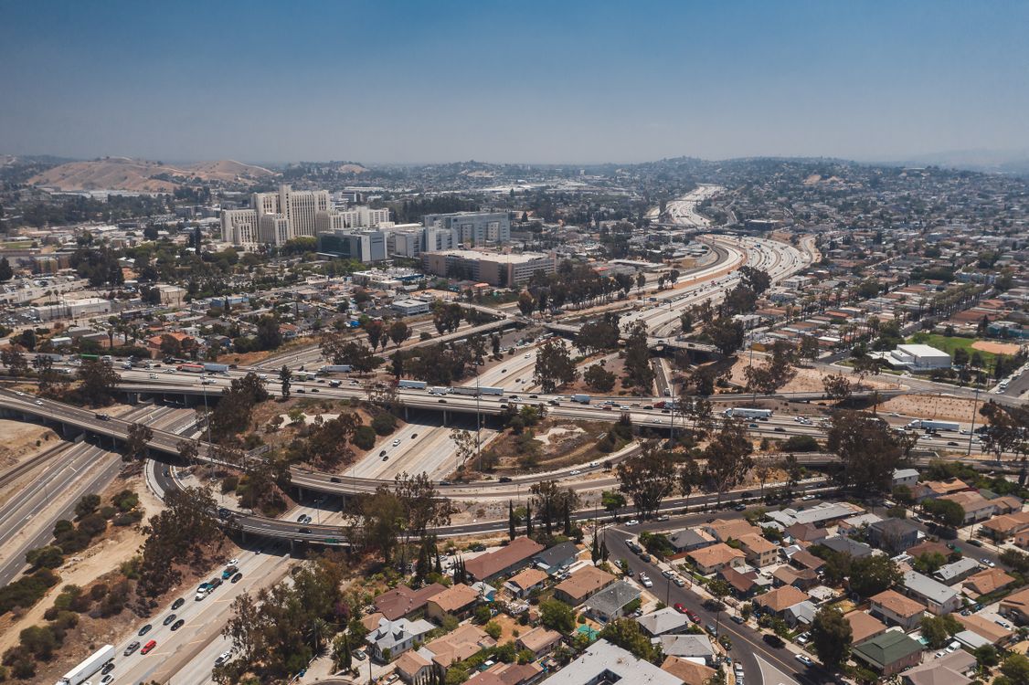 Vista aérea de grandes cruzamentos rodoviários em Los Angeles, representando investimentos e benefícios que dependem de várias frentes conectadas