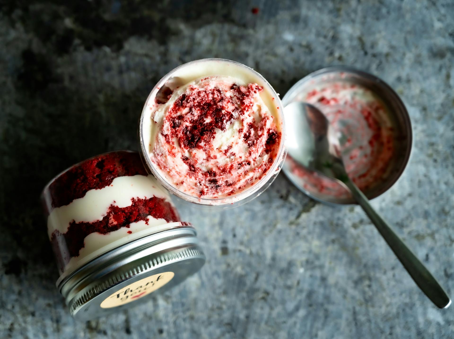 Close-up of a creamy red velvet cake in a jar with spoon, perfect for dessert lovers.