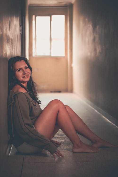 Smiling Woman Sitting on Corridor Floor