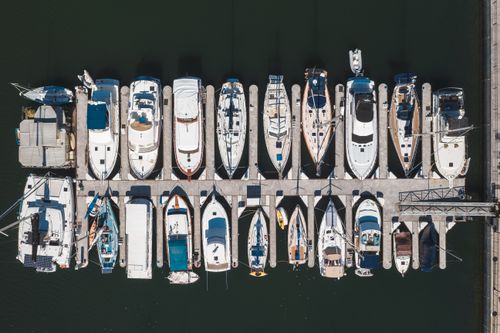 Free Drone shot capturing yachts and boats docked in a marina harbor from above. Stock Photo