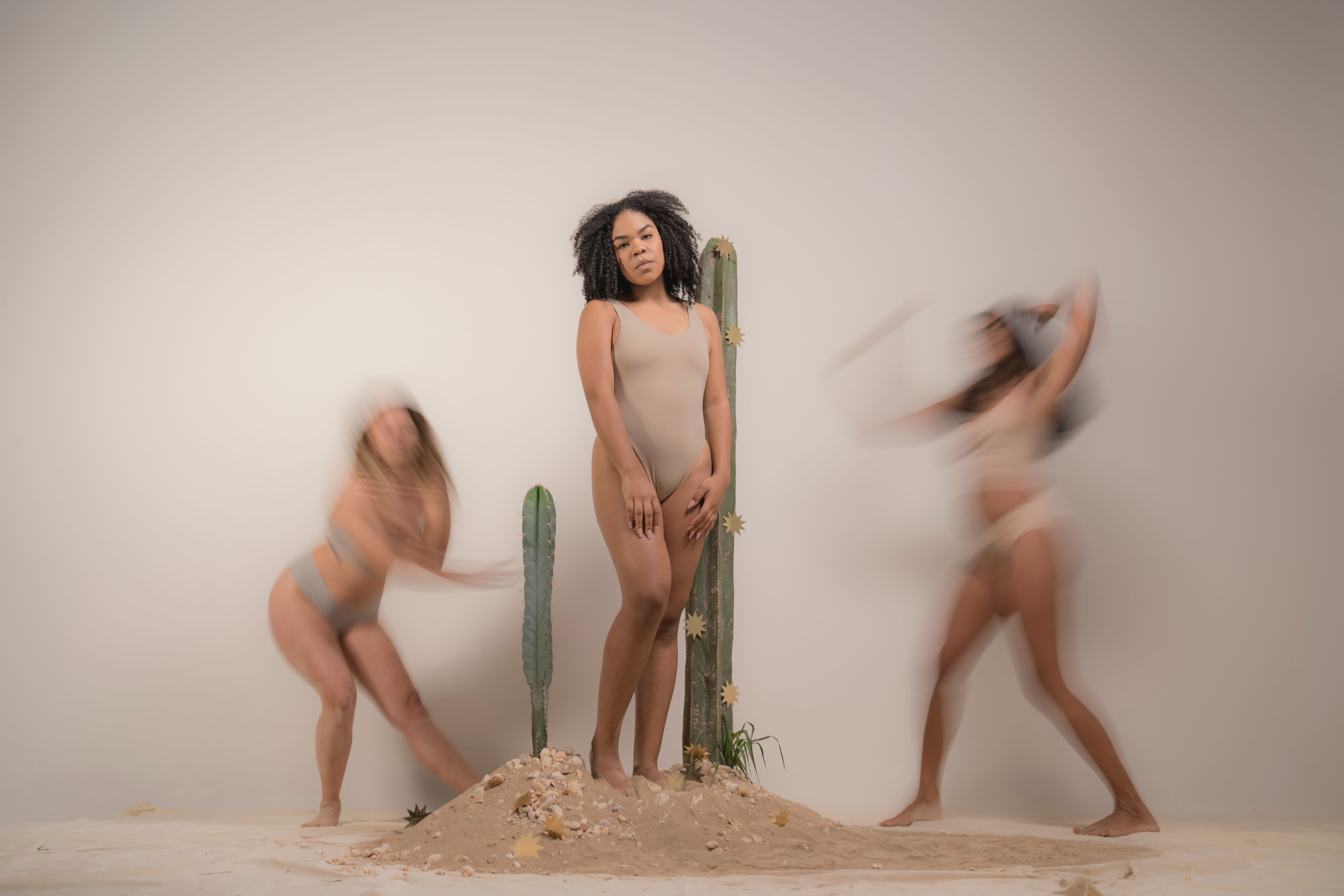 Free Three diverse women express empowerment with cactus in artistic desert setting. Stock Photo