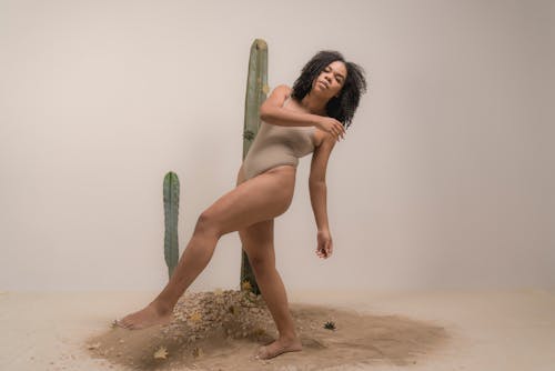 Woman in Gray Bikini Posing on Brown Sand Beside Cactus 