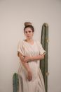 Woman in White Long Sleeve Dress Standing Beside Green Cactus