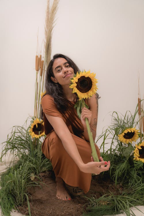 A Woman in Brown Dress Holding a Sunflower