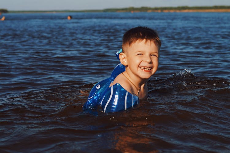 Boy Smiling While Swimming On The Lake