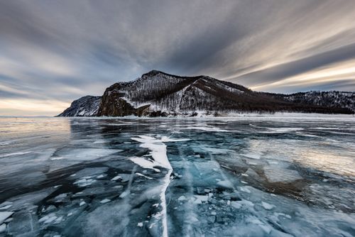 Free Stunning view of frozen Lake Baikal during winter with dramatic skies and snow-covered mountains. Stock Photo