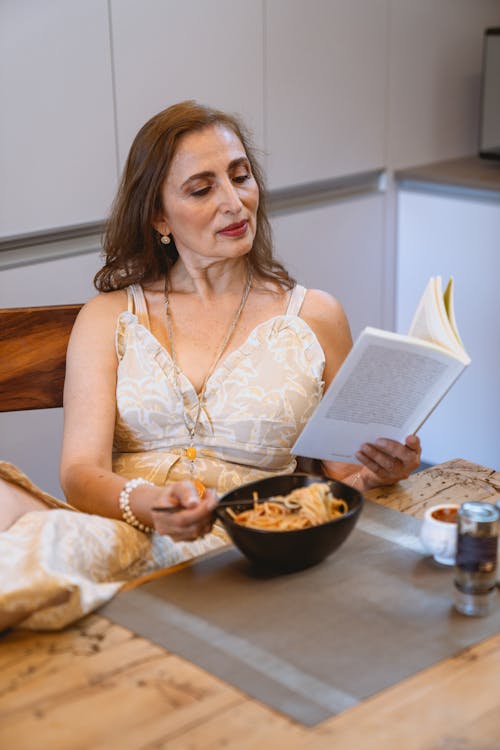Darmowe zdjęcie z galerii z bez rękawów, czytając książkę, jedzenie